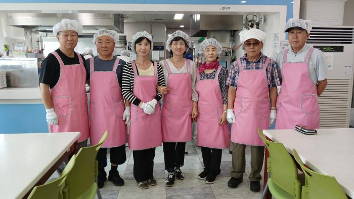 6월 25일 문산종합사회복지관 급식소에서 배식봉사에 참여한 문산금요트레킹 동아리 회원들이 분홍 앞치마를 입고 기념촬영을 하고 있다