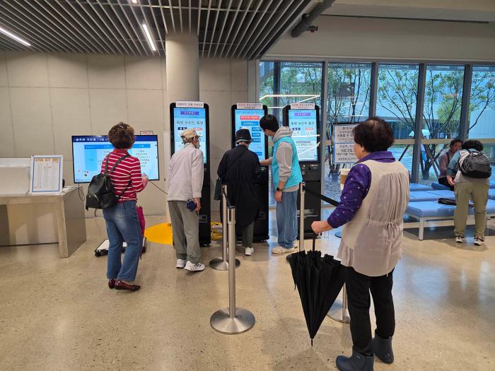 봉사원들이 키오스크 사용법을 도와주고 있다고